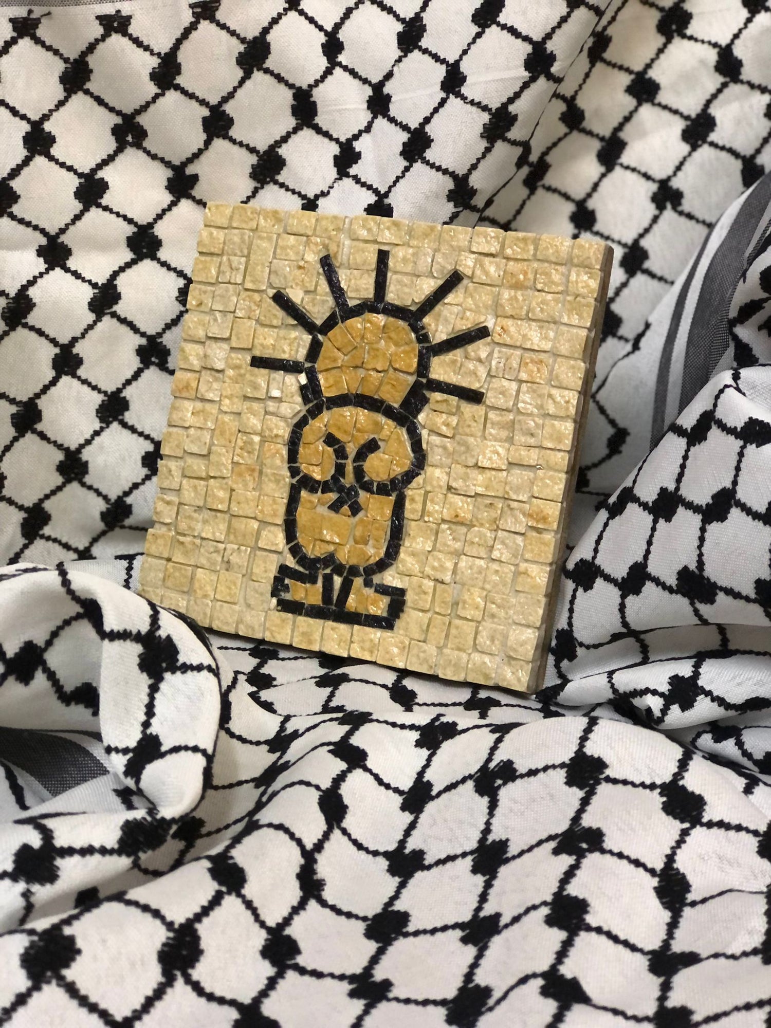  handala Mosaic artwork of a stylized face on a checkered fabric background
