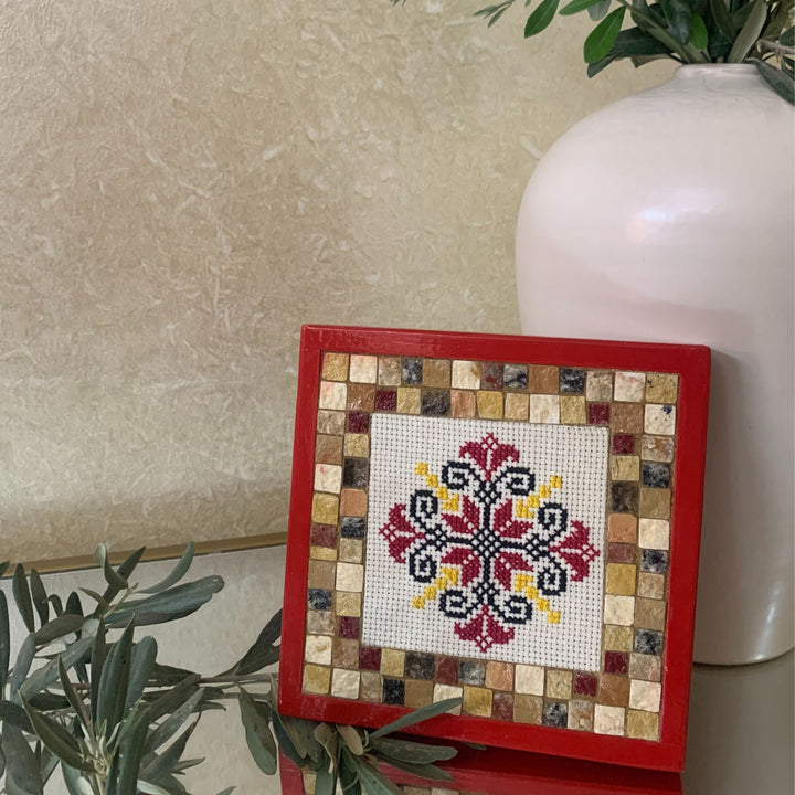 Decorative mosaic art piece with a red frame on a neutral background