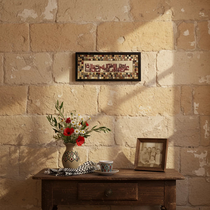 Decorative setting with a vase of flowers, framed picture, and decorative items against a stone wall.