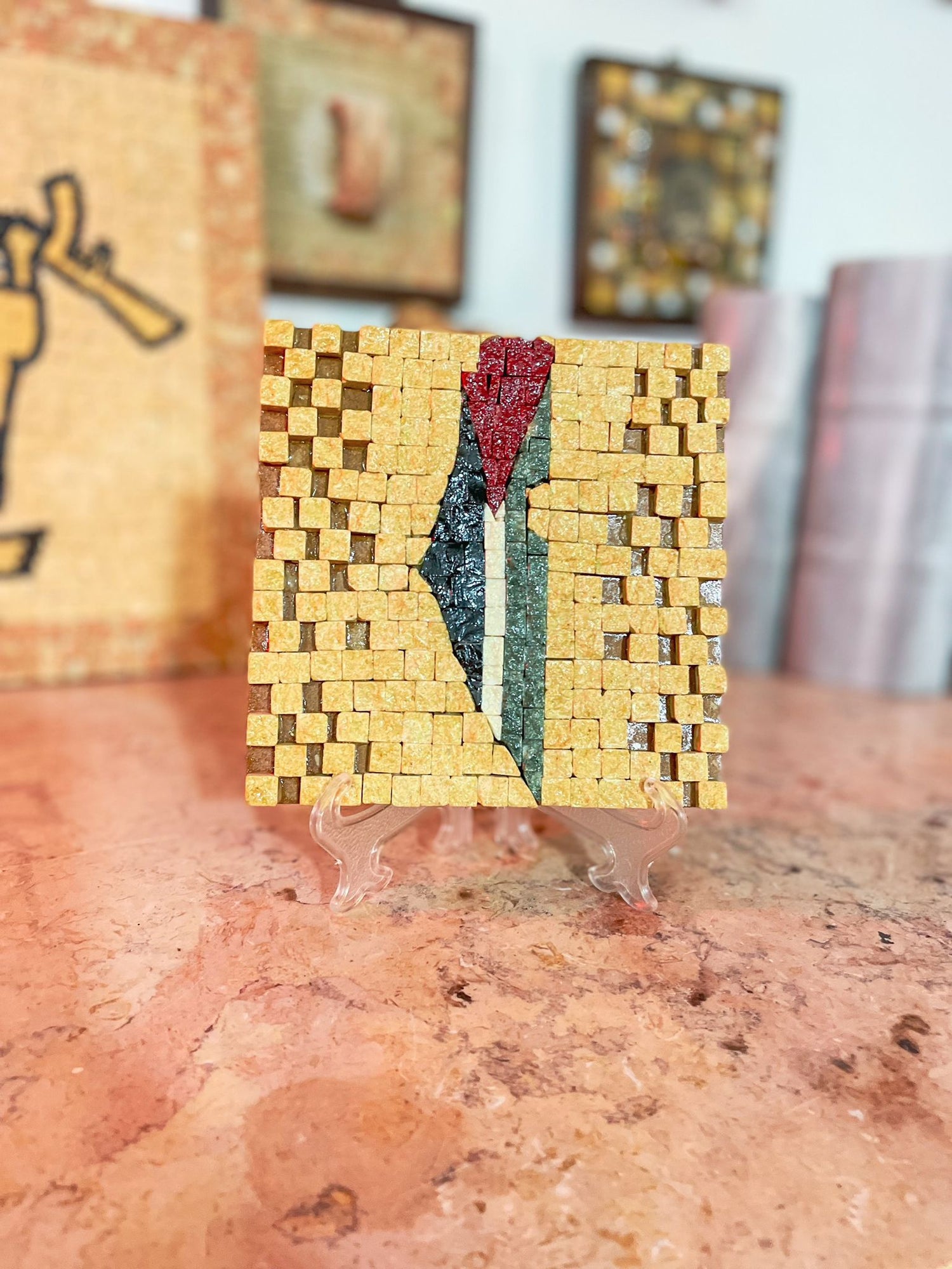 Small square mosaic art piece on a stand with a blurred background